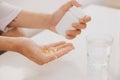 Hand takes yellow capsules of omega 3, white pills of glucosamine and calcium on plastic box, glass with water at wooden table, t Royalty Free Stock Photo