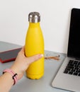 Hand takes yellow insulated bottle