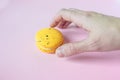 Hand takes yellow macaroon, pink background