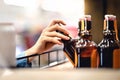 Hand taking bottle of beer from shelf in alcohol and liquor store. Customer buying cider or supermarket staff filling and stocking