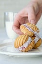 A hand taking cookies from a white plate on white background with glass of milk Royalty Free Stock Photo