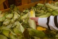 hand taking corn from grocery store shelf