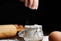 Hand taking flour from a bowl with eggs and a rolling pin on the table Royalty Free Stock Photo