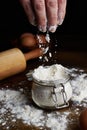 Hand taking flour from a bowl with eggs and a rolling pin on the table Royalty Free Stock Photo