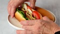 Hand taking a hot dog off a plate