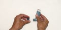 hand taking off cap of bronchial asthma spray inhaler with white background