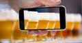 Hand taking picture of beer glasses through smart phone at bar Royalty Free Stock Photo