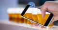 Hand taking picture of beer glasses through smart phone Royalty Free Stock Photo