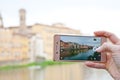 Hand taking picture of Florence waterfront with St Trinity Bridge over river on smartphone, Italy Royalty Free Stock Photo