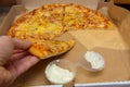 Hand taking a piece of pizza out of the box