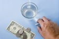 Hand taking pills from the pastel blue desk, glass of water, mon Royalty Free Stock Photo