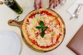 A hand taking slice of hot served Pizza Margherita on wooden plate with olive oil Royalty Free Stock Photo