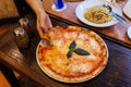 Hand taking slice of Margarita pizza topping with basil leaves served with oregano and chili powder Royalty Free Stock Photo