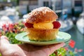 Hand with Tarte tropezienne or La Tarte de Saint-Tropez - dessert pastry consisting of filled brioche with cream and fresh berries