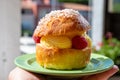 Hand with Tarte tropezienne or La Tarte de Saint-Tropez - dessert pastry consisting of filled brioche with cream and fresh berries