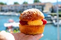 Hand with Tarte tropezienne or La Tarte de Saint-Tropez - dessert pastry consisting of filled brioche with cream and fresh berries