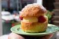 Hand with Tarte tropezienne or La Tarte de Saint-Tropez - dessert pastry consisting of filled brioche with cream and fresh berries