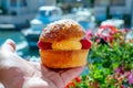 Hand with Tarte tropezienne or La Tarte de Saint-Tropez - dessert pastry consisting of filled brioche with cream and fresh berries