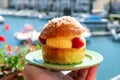 Hand with Tarte tropezienne or La Tarte de Saint-Tropez - dessert pastry consisting of filled brioche with cream and fresh berries