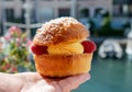 Hand with Tarte tropezienne or La Tarte de Saint-Tropez - dessert pastry consisting of filled brioche with cream and fresh berries