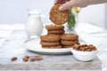 Hand with tasty oatmeal almond cookies with jar of milk on the old marble table beautiful close-up on white background Royalty Free Stock Photo