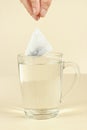Hand with the tea bag above cup of boiling water Royalty Free Stock Photo