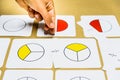 Hand of teacher montessori guide graphically shows fractions with mathematical cards