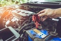 Hand of technician checking battery terminals and engine on the