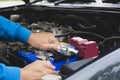 Hand of technician checking engine of car.