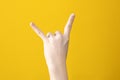 hand of teen with two raised fingers in shape of goat with yellow background. Popular youth gesture Royalty Free Stock Photo