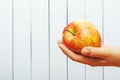 Hand of teenage girl with apple on wooden background with cpy space. Side view. Ecologic clean fresh fruit