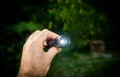 Hand testing holding new mini flashlight torch green defocused outdoor Royalty Free Stock Photo