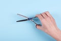 Hand with thinning scissors on a blue background composition