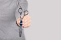 Hand with thinning scissors on grey background