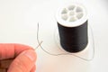 Hand threading a needle with black thread