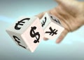 Hand throwing 2 dice with currency symbols. Concept for financial advice, trading, markets.