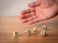 Hand throwing five dice on a wooden table Royalty Free Stock Photo