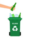 Hand throwing green glass bottle into a recycle bin.