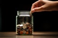 A hand throws coins into a jar with coins. Savings, capital