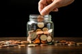 A hand throws coins into a jar with coins. Savings, capital