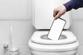 the hand throws the phone with an empty white screen into the toilet or trash can. mockup layout for labels