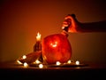 A hand thrusts a knife into a comically carved Halloween pumpkin on a table, surrounded by lanterns and a lit candle Royalty Free Stock Photo