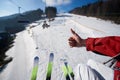 Hand with thumb-up gesture and skis on background of mountain ski-lift rope way on winter day. Royalty Free Stock Photo