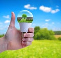 Hand with thumb up holding a eco LED bulb with solar panel.