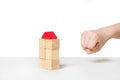 Hand about to destroy house made of wooden blocks