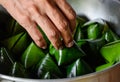 Hand to holding Thai desserts in a steaming container, Thai desserts wrapped in banana leaves shaped into a three-dimensional Royalty Free Stock Photo