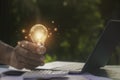 Hand toching light bulbs and book opening on wooden table