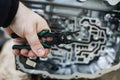 Hand with tool against the background of an automatic transmission with shallow depth of field