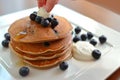 hand topping pancake stack with blueberries, yogurt on side Royalty Free Stock Photo