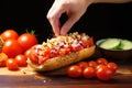 hand tossing diced tomato over a gourmet hot dog